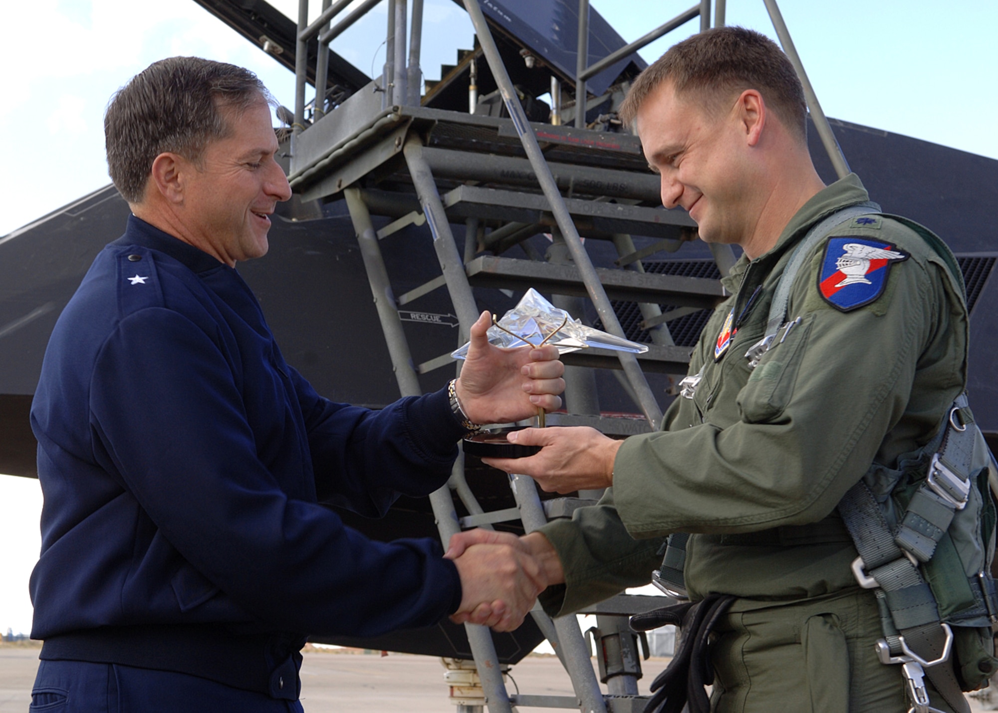 Lt. Col. Kenneth Tatum, 9th Fighter Squadron commander, recieves a crystal Nighthawk from Brig. Gen. David Goldfein, 49th Fighter Wing commander, for his milestone 1,000 hour flight in the F-117A Dec.7. Colonel Tatum is the last F-117 pilot to achieve this milestone before the retirment of the F-117 next year. (U.S. Air Force photo/Airman 1st Class John Strong)