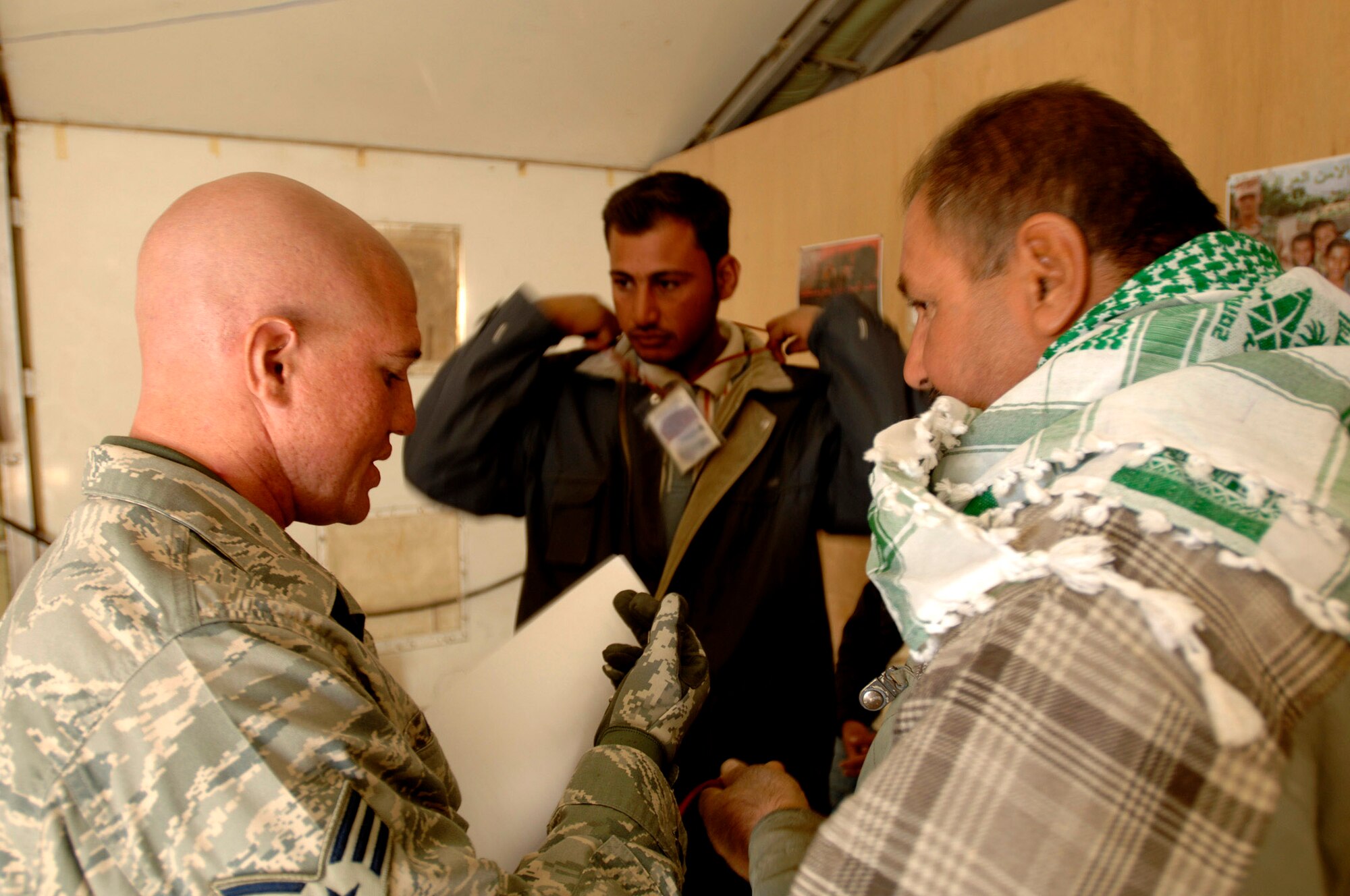 Senior Airman Paul Rael hands local Iraqi nationals passes so they can work on base Nov. 27. Airman Rael is assigned to the 407th Expeditionary Security Forces Squadron force protection and is responsible for escorting and supervising the local nationals as they work. Airman Rael is an aircraft metals technology machinist from Whiteman Air Force Base, Mo. (U.S. Air Force photo/Airman 1st Class Jonathan Snyder)