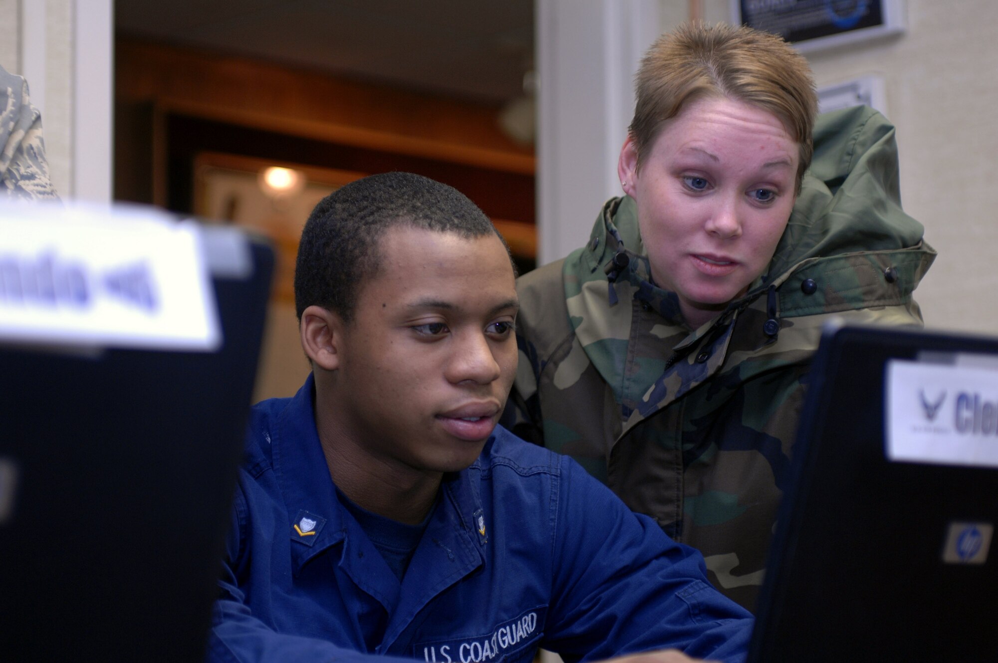 Coast Guard Petty Officer 3rd Class Perry Clement and Senior Airman Emily Burgess, Airman Leadership School students, look at some of the curriculum at the Elmendorf Professional Military Education Center Nov. 29. Petty Officer Clement is a machinery technician for District 17. (U.S. Air Force photo/Airman 1st Class David Carbajal)
