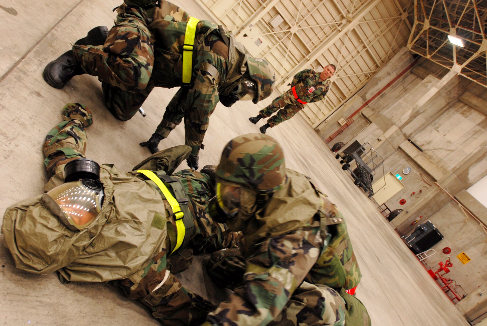 Tech. Sgt. Forest Sell and Senior Airman Victor Cross don Senior Airman Tyler Willing's mask for him and determine the need to administer the nerve agent antidote treatment while exercise evaluation member Master Sgt. Jefferson Baggett watches their progress during an operational readiness exercise Dec. 4 at Kadena Air Base, Japan. The Airmen are from the 718th Aircraft Maintenance Squadron and 961st Aircraft Maintenance Unit. (U.S. Air Force photo/Staff Sgt. Chrissy FitzGerald) 