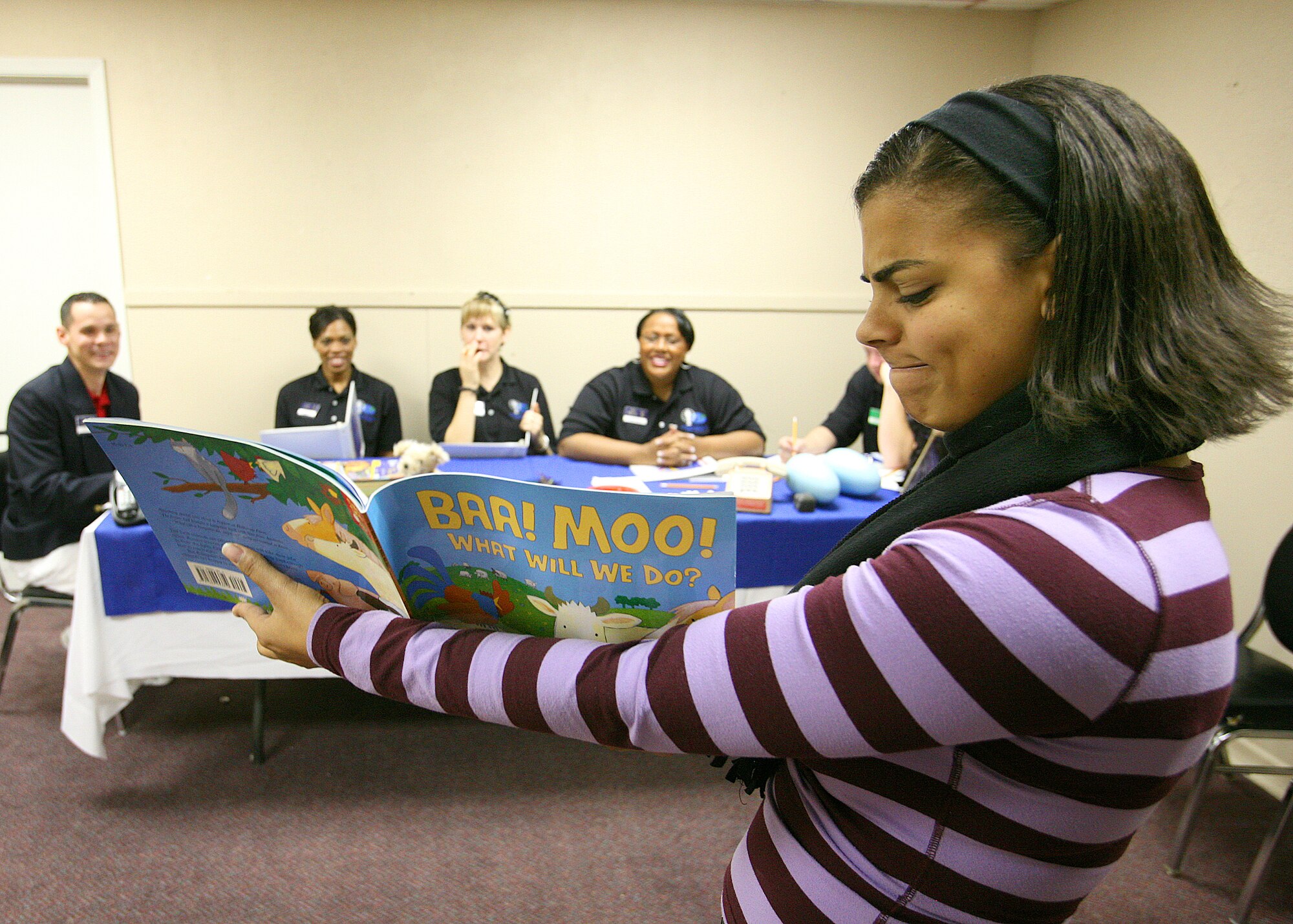 Senior Airman Shala Baugh, a linguist from Offutt Air Force Base, Neb., reads from a children's book as she tries to impress a panel of former and current Tops in Blue members. Airman Baugh is a competitor in the Air Force World Wide Talent Contest held at Lackland AFB, Texas, from Dec. 2-10.  The talent contest is the first step to Tops in Blue.  (U.S. Air Force photo/Robbin Cresswell) 
