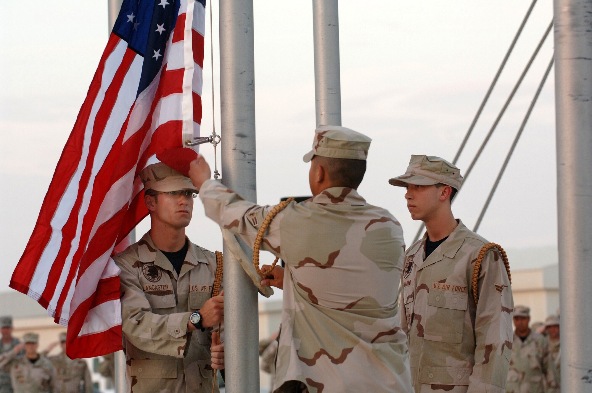 SOUTHWEST ASIA - Members of the 379th Air Expeditionary Wing honor guard, prepare to remove the flag from the flag staff after it was lowered during a Retreat ceremony in honor of those who have fallen and survived the attack on Pearl Harbor 66 years ago today at a Southwest Asia air base. Members of the honor guard detail are Airmen 1st Class Jesse Lancaster (left), Huy-Ryan Nguyen (center) and George Navarro. (U.S. Air Force photo/Master Sgt. Greg Kunkle)