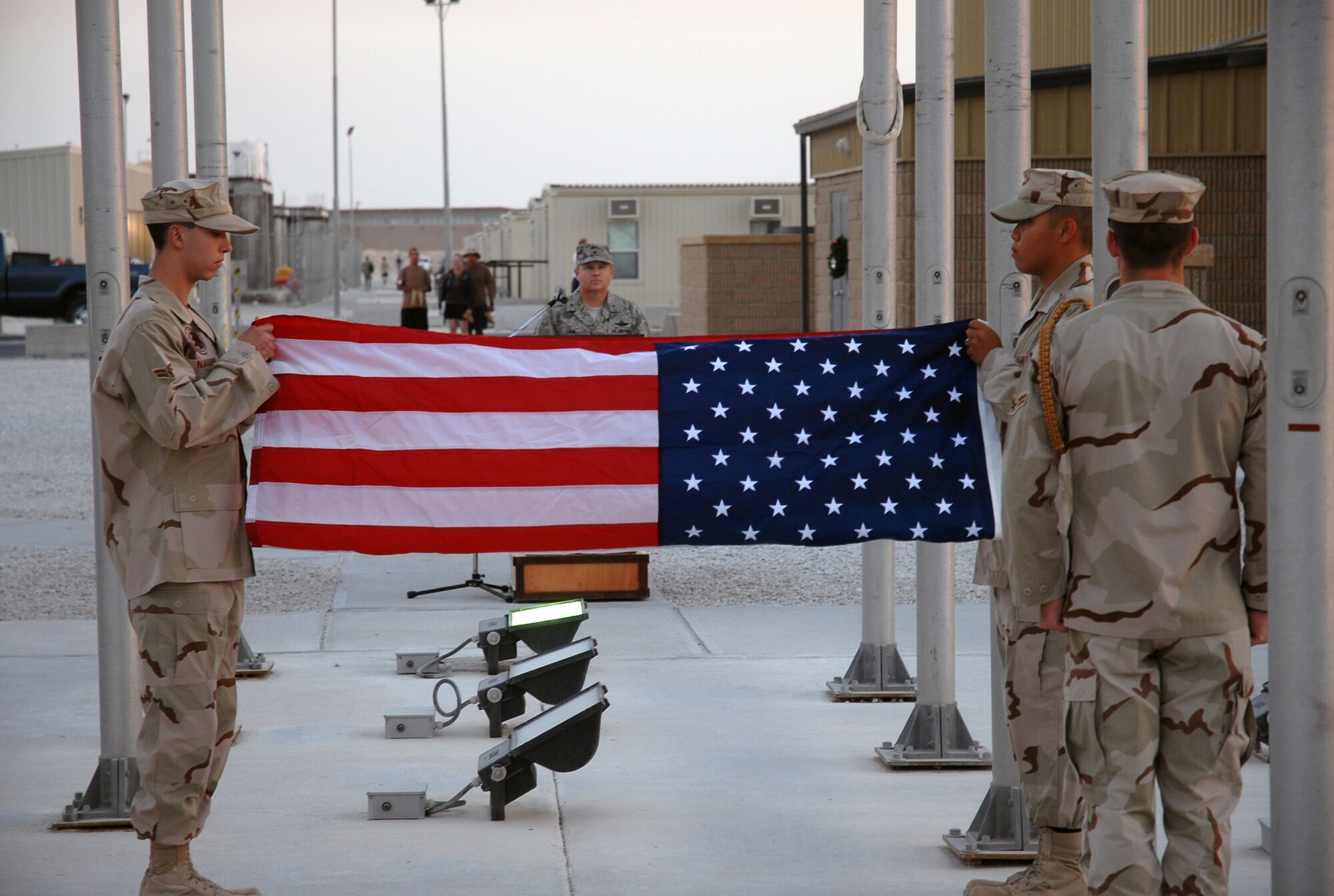 SOUTHWEST ASIA - Airmen First Class George Navarro and Huy-Ryan Nguyen fold the flag while Jesse Lancaster stand by during a Retreat Ceremony in honor of the attack on Pearl Harbor 66 years ago today at a Southwest Asia air base. All of the Airmen are members of the 379th Air Expeditionary Wing honor guard. Brig. Gen. Charlie Lyon, 379th AEW commander, stands at attention in the background. (United States Air Force photo/Staff Sgt. Douglas Olsen)