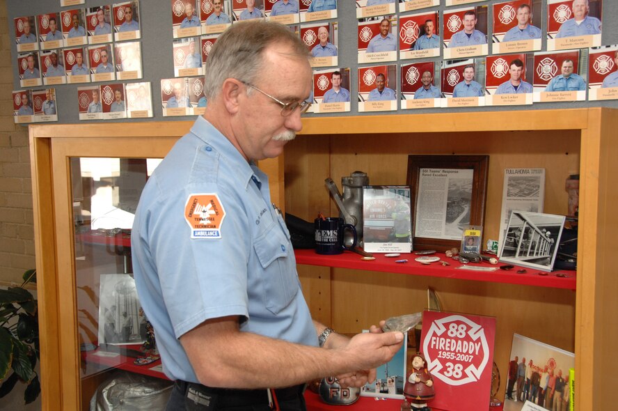 Arnold Engineering Development Center Firefighter and Crew Chief Charlie Armstrong examines a partially melted fragment of a glass port (observation window) from the J-5 rocket engine test cell ? a piece of debris from the explosion he and his coworkers responded to in 1985. Armstrong and others at the center’s fire department have assembled a range of artifacts, including damage debris, old fire fighting equipment, photographs and other memorabilia collected over the years and put them into a display case at the fire hall.  (Photo by David Housch)