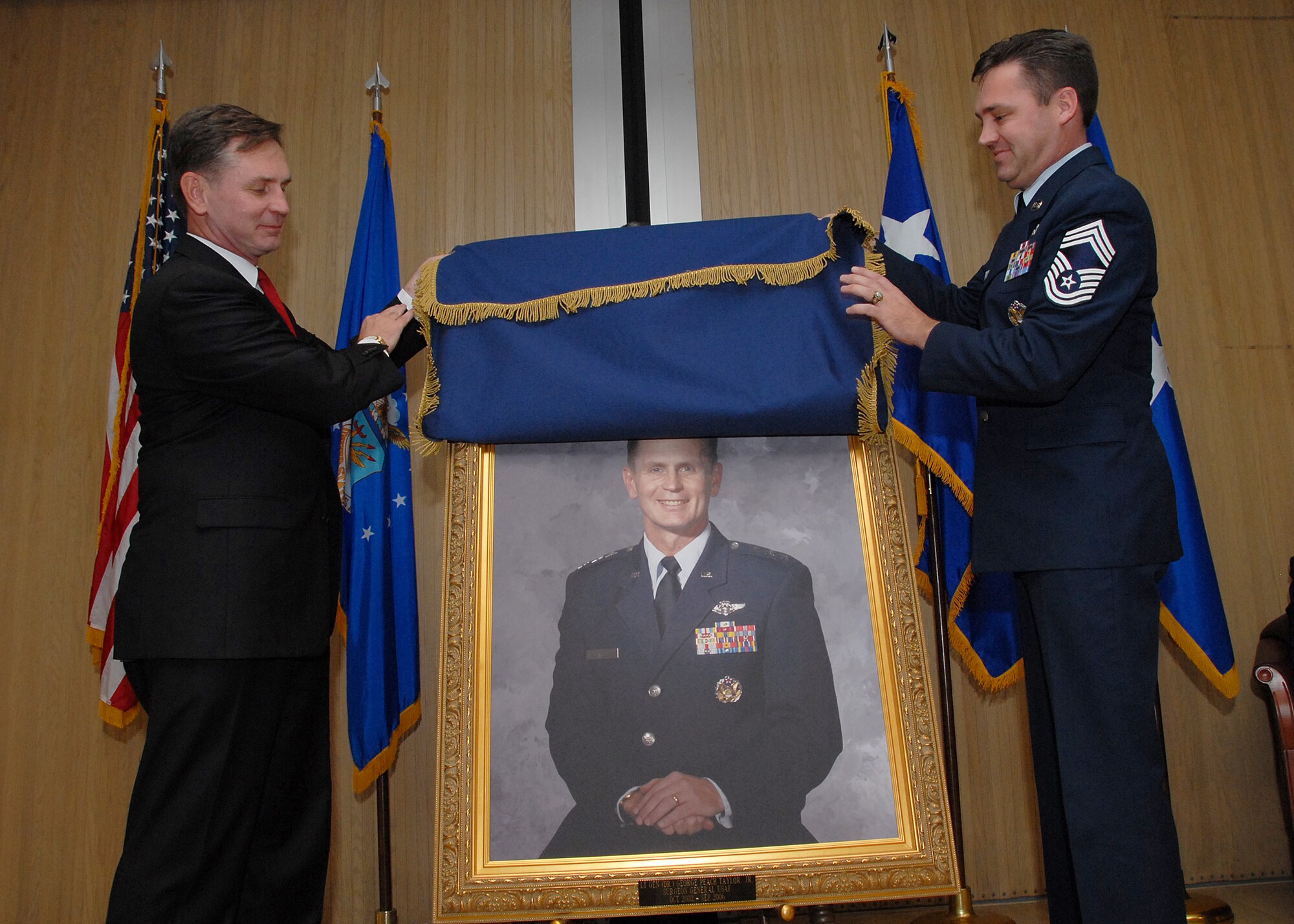 Retired Lt. Gen. George Taylor, former Surgeon General of the Air Force, and Medical Enlisted Force Chief Chief Master Sgt. Mark Withers present General Taylor's portrait at the unveiling ceremony Dec. 5.  The portrait will hang in Bldg. 1900.  (U.S. Air Force photo/Mike Litteken)