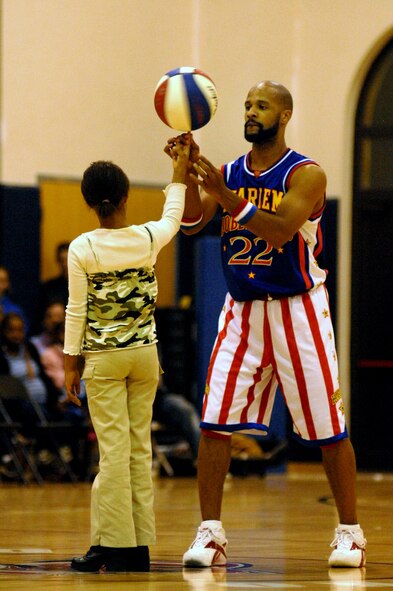 Harlem Globetrotter "Flight Time" helps Jaz'men Ashe spin a basket ball on one finger during the Harlem Globetrotters exhibition game Dec. 1 at the Dragon Fitness Center at Aviano Air Base, Italy. The Harlem Globetrotters are touring Army and Air Force installations throughout Europe as part of their "Magic As Ever" 2008 world tour. (U.S. Air Force photo/Airman 1st Class Tabitha M. Mans)