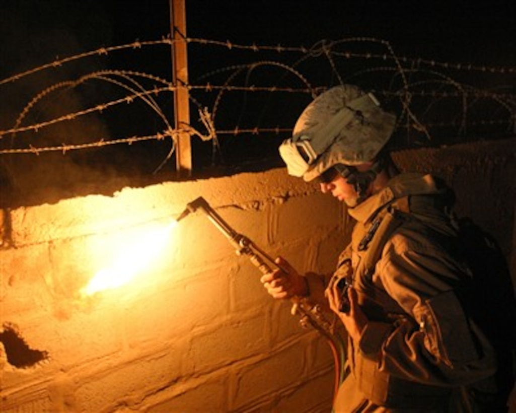 U.S. Marine Corps Lance Cpl. Gabriel Sheridan lights his acetylene torch as he prepares to remove barbed wire in Karmah, Iraq, on Nov. 17, 2007.  Sheridan and his fellow combat engineers from the 3rd Battalion, 3rd Marine Regiment, are expanding the berthing area at an observation post in Karmah, Iraq.  