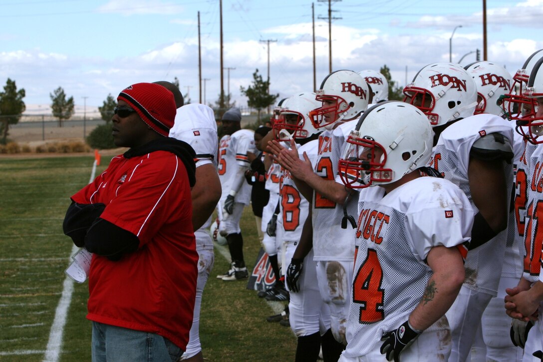 Daymian Brown, Headquarters Battalion head coach, and his team intently watch the current play from their sideline at the Best of the West Football Championship at Felix Field Dec. 8.