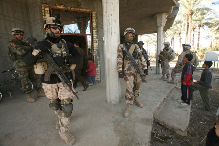 An Iraqi soldier with 1st Battalion, 3rd Brigade, 1st Iraqi Army Division stands watch along other soldiers outside a school near Abu Hazim Dec. 8. MTT 1-3-1 is currently deployed within Iraq?s Al Anbar Province to help develop Iraqi Security Forces, facilitate the development of official rule of law through democratic government reforms and continue the development of a market based economy centered on Iraqi reconstruction.