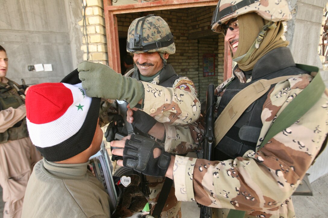 Iraqi army soldiers with 1st Battalion, 3rd Brigade, 1st Iraqi Army Division joke with a young boy at a school near Abu Hazim Dec. 8. MTT 1-3-1 is currently deployed within Iraq?s Al Anbar Province to help develop Iraqi Security Forces, facilitate the development of official rule of law through democratic government reforms and continue the development of a market based economy centered on Iraqi reconstruction.