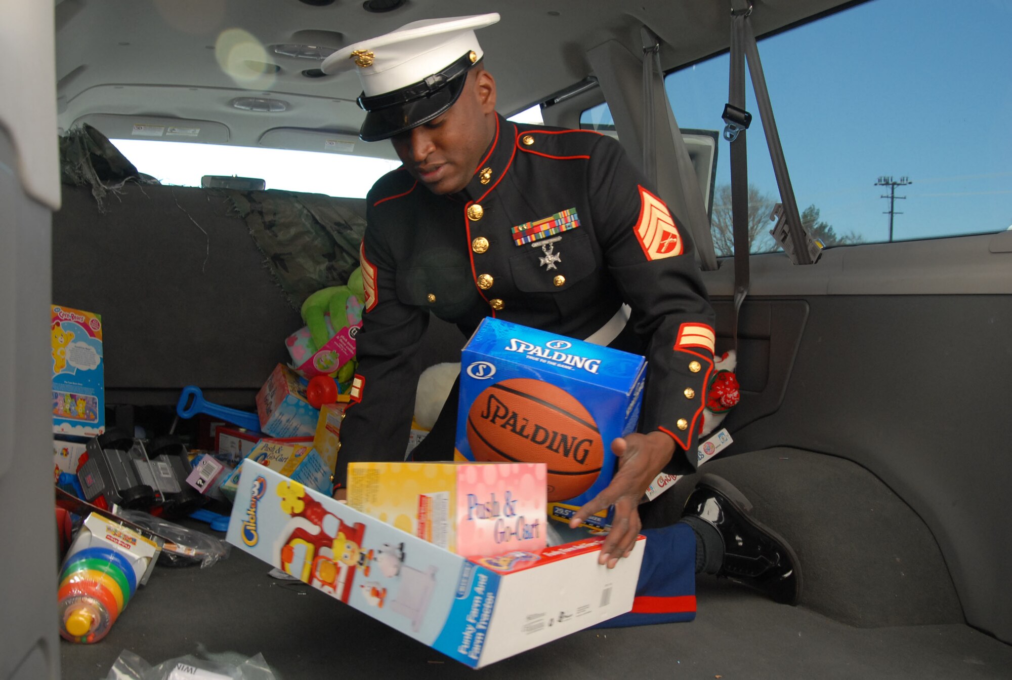 Marine Staff Sgt. Quinton Taylor, Marine Heavy Helicopter Squadron 769 helicopter mechanic and Toys for Tots coordinator, carries toys for the Angel Tree program Dec. 10 here. The Marine Aircraft Group 46 Detachment Bravo here delivered 250 toys for the Angel Tree program. The Angel Tree program traditionally provides gifts for children of families on base who are in need and have deployed parents. (Photo by Senior Airman Julius Delos Reyes)