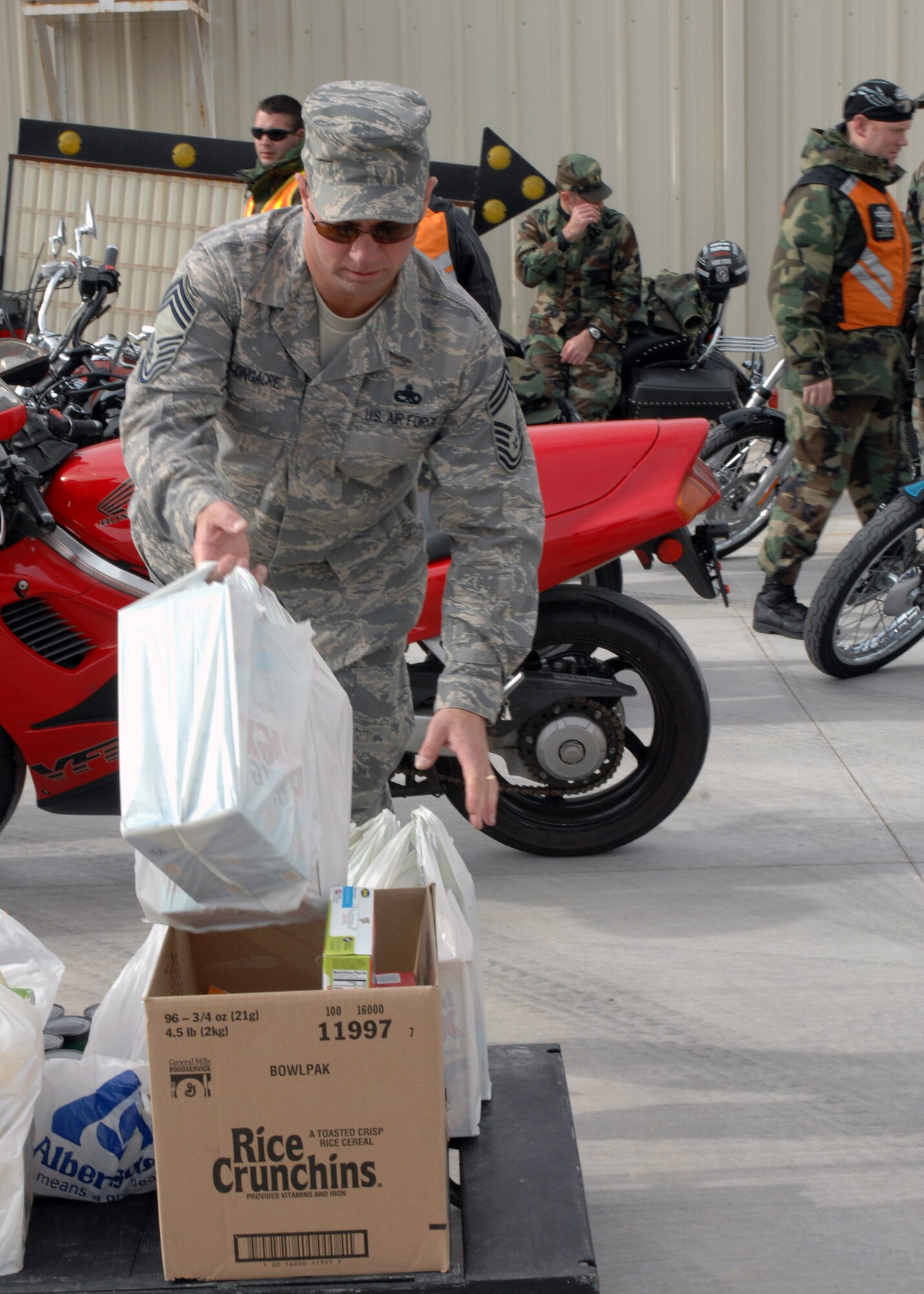 Chief Master Sgt. Kenneth Longacre  drops bags of food into a box at the Clovis Food Bank Dec. 6 in New Mexico. Chief Longacre is the 27th Special Operations Mission Support Group superintendent and member of the motorcycle riders group at Cannon Air Force Base, N.M. The group took donated food to the food bank to share in the holiday spirit. (U.S. Air Force photo/Airman 1st Class James Bell)
