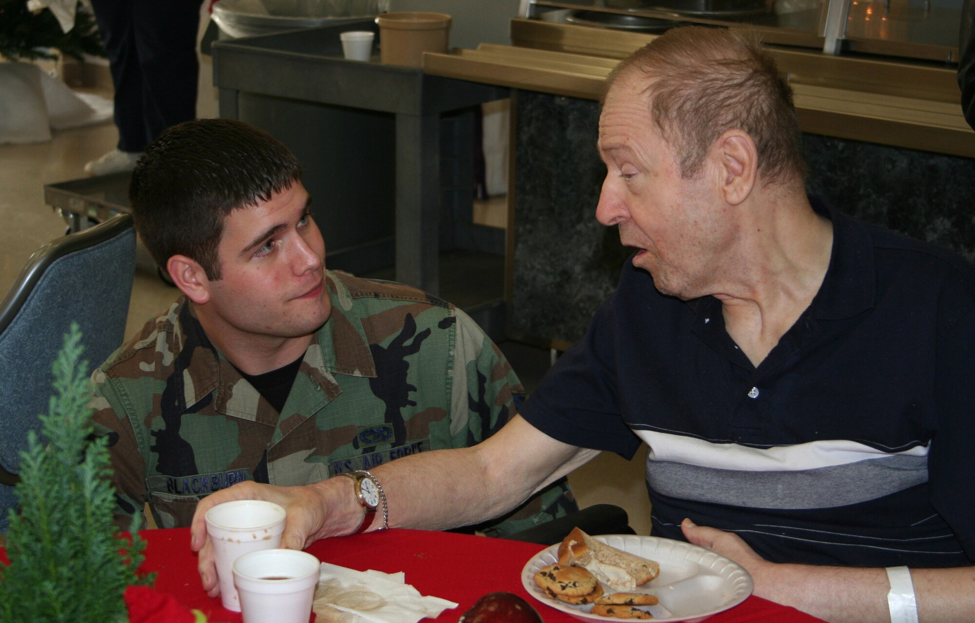 DAYTON, Ohio - Senior Airman Ross Blackburn from the 87th Aerial Port Squadron, a squadron within the 445th Airlift Wing, talks with a VA resident at their annual Christmas Party.  The Air Force Sergeants Association has been hosting parties such as this one at the VA center for almost 20 years.  This was the 11th year the 445th Airlift Wing has helped with the party. (U.S. Air Force photo/Tech. Sgt. Charlie Miller)