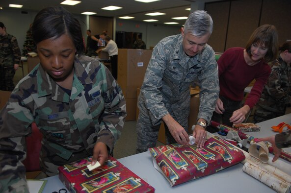 MOODY AIR FORCE BASE, Ga. — Airman Marquita Smith, 23rd Logistics Readiness Squadron training technician, Col. Kenneth Todorov, 23rd Wing commander, and his wife Lynn wrap gifts Dec. 6 during the Moody Chapel's Adopt-a-Family program.  The chapel has sponsored the program, which has Team Moody members donate items for families in surrounding communities, for the past 30 years.  (U.S. Air Force photo by Senior Airman Angelita Lawrence) 
