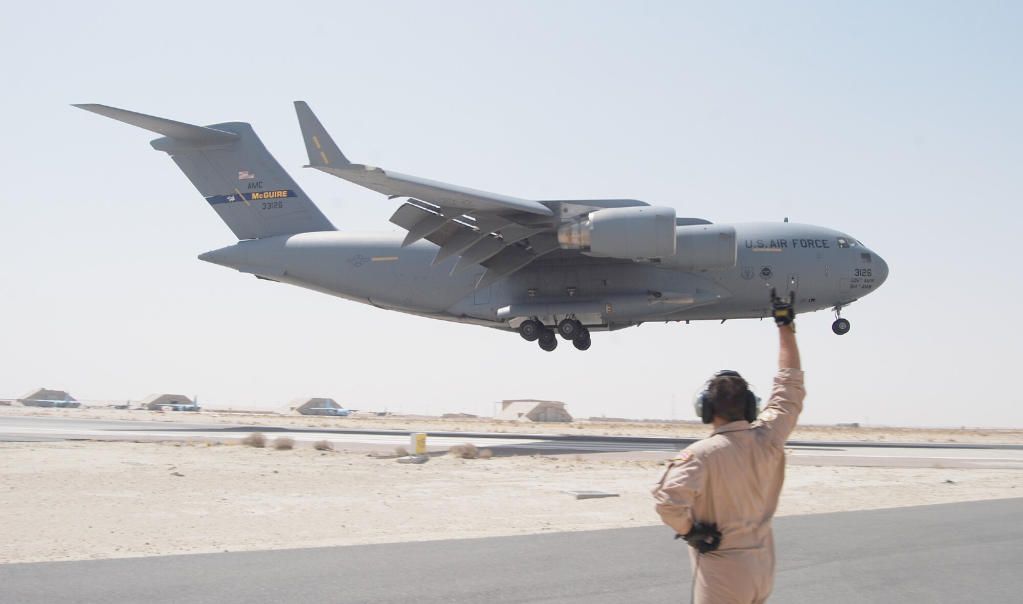 Staff Sgt. Cory Rich, deployed with the 6th Airlift Squadron from McGuire AFB, N.J., greets a McGuire C-17 as it lands at a base in the AOR. The squadron recently delivered its 100,000th pound of cargo and 100,000th servicemember to the AOR after just 90 days of being deployed as the 816th Expeditionary Airlift Squadron. (U.S. Air Force photo/1st Lt. Michael Motschman)
