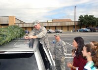 Stephanie Cooper and her children watch as Col. Eric Wilbur, 37th Training Wing vice commander at Lackland Air Force Base, Texas, secures a Christmas tree to their vehicle Dec. 6 at the Outdoor Recreation Center. An additional 40 trees were hand-delivered to families who have a deployed member. (USAF photo by Alan Boedeker)                               