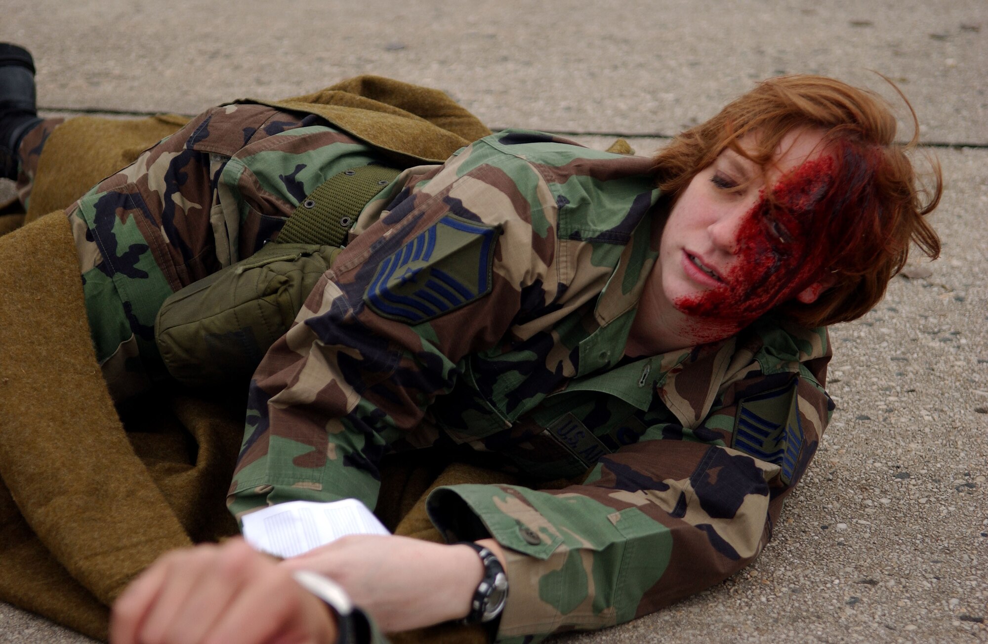 SPANGDAHLEM AIR BASE, Germany -- Airman 1st Class Michelle Moffett, 52nd Medical Support Squadron Pharmacy technician, simulates struggling to drag herself across the cold pavement while trying to flag down medical assistance during a mass-casualty exercise held as part of a base-wide training week here. (U.S. Air Force photo/Senior Airman Matthew S. Bright) 