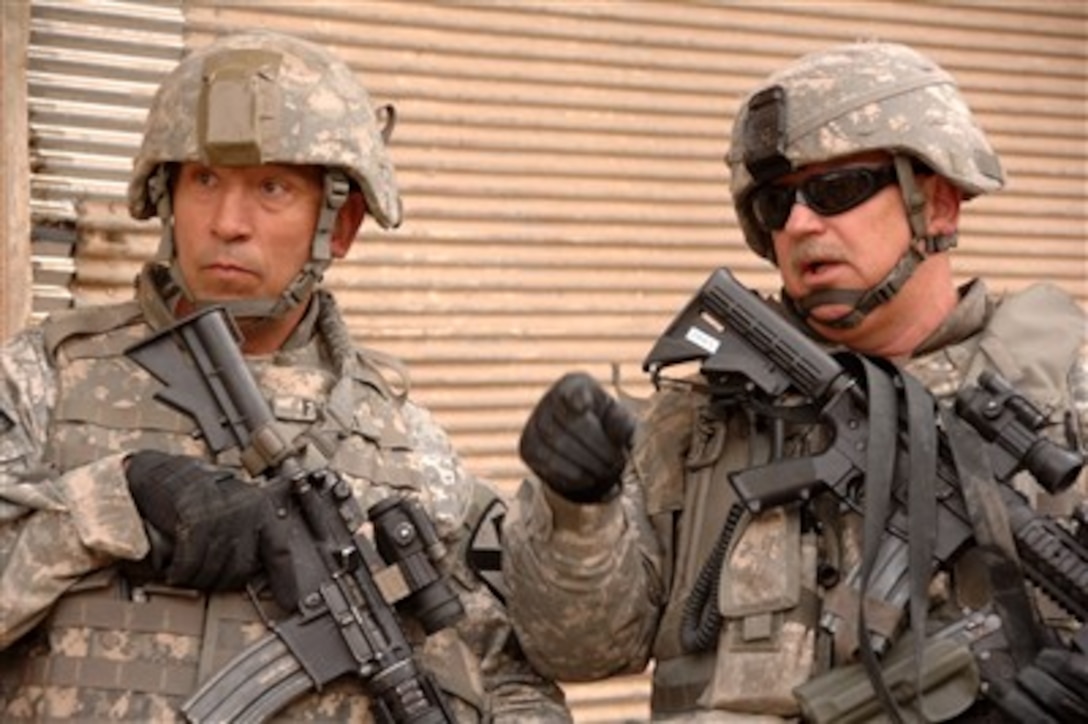 U.S. Army Lt. Col. Hubert Pries (right) talks with another soldier while patrolling through a neighborhood of Mosul, Iraq, on Dec. 1, 2007. Pries and his fellow soldiers attached to the 2nd Iraqi Army Division Military Transition Team work side-by-side with the Iraqi army, assisting and advising them on the fight against the insurgency. 