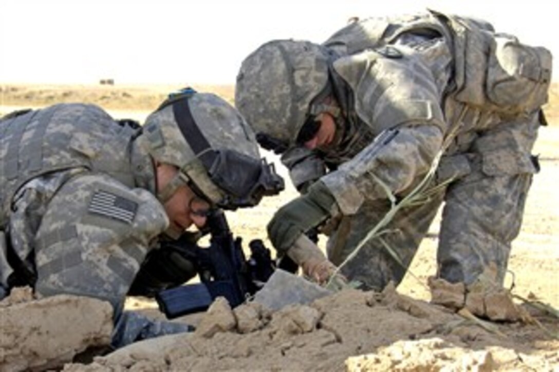 U.S. Army Sgt. 1st Class Travis Johnson and Spc. Daniel McEleney, search for a weapons cache in Tarafawee, Iraq, Nov. 30, 2007, after being tipped off by an informant. Johnson and McEleney are assigned to the 10th Mountain Division, 1st Brigade Combat Team, 6th Field Artillery Regiment.