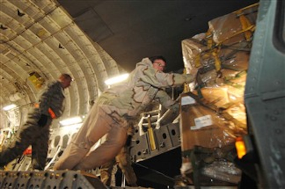 U.S. Air Force Senior Master Sgt. Dan Lynch, pushes a pallet of humanitarian supplies, donated by U.S. Air Force Lt. Gen. John Bradley, commander of Air Force Reserve Command, and his wife, out of an  aircraft at Bagram Air Base, Afghanistan, Dec. 2, 2007. Lynch is assigned to the  729th Airlift Squadron.