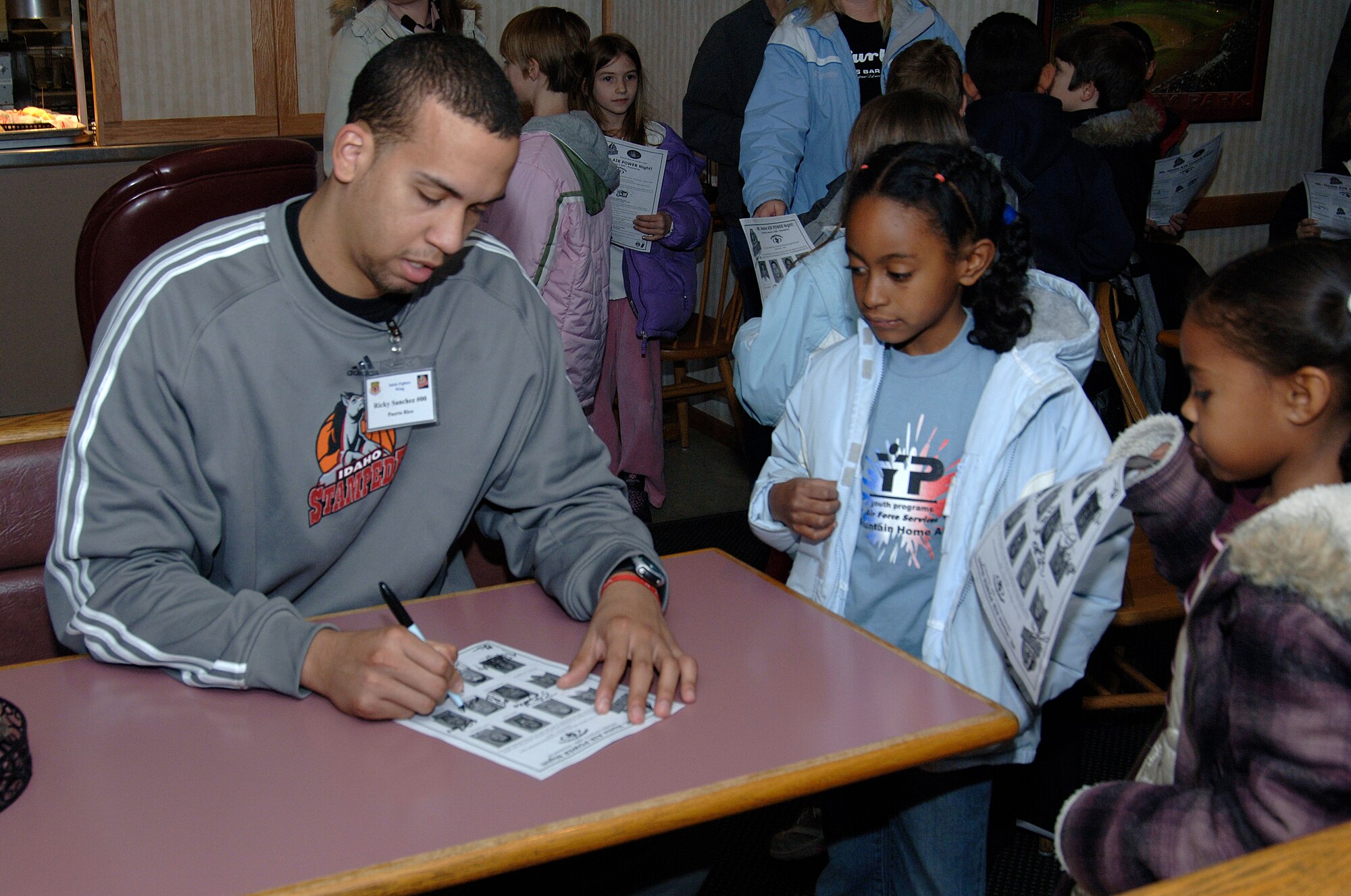 MOUNTAIN HOME AIR FORCE BASE, Idaho -- Ricky Sanchez, a member of the Idaho Stampede basketball team, signs autographs for children here Dec.10. The Idaho Stampede is a member of the NBA D-league with its base of operations in Boise, Idaho. (U.S. Air Force photo/ Staff Sgt. Rodney D. Ivey)