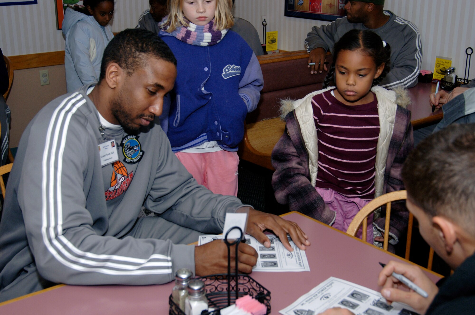 MOUNTAIN HOME AIR FORCE BASE, Idaho -- Ernest Scott, a member of the Idaho Stampede basketball team, signs autographs for children here Dec.10. The Idaho Stampede is a member of the NBA D-league with its base of operations in Boise, Idaho. (U.S. Air Force photo/ Staff Sgt. Rodney D. Ivey)