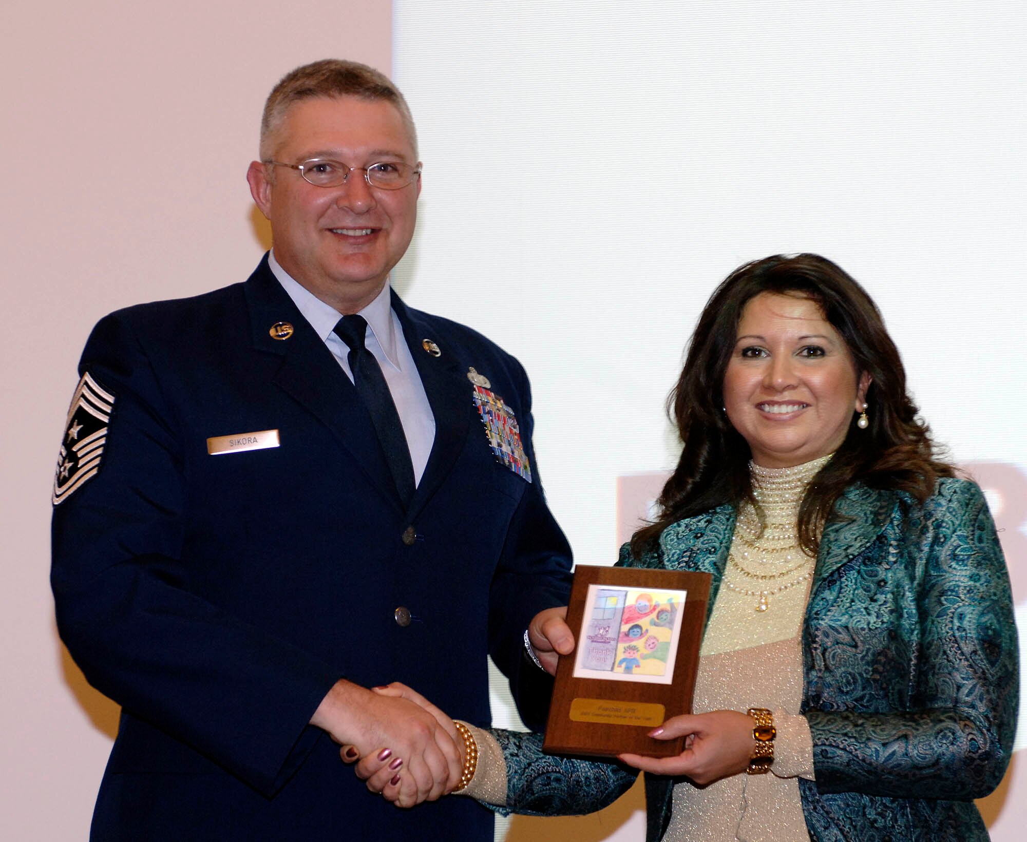 FAIRCHILD AIR FORCE BASE, Wash. –Chief Master Sgt. Paul Sikora, 92nd Air Refueling Wing command chief, receives the Big Brothers Big Sisters of the Inland Northwest Community Partner of the Year Award on behalf of Team Fairchild from Melissa Perea, BBBS fundraiser event coordinator, at the BBBS awards ceremony on Dec 6. at the Spokane Valley center. Fairchild received the award for being a major contributor of volunteers to the traditional and school-based BBBS programs. (U.S. Air Force photo/Staff Sgt. JT May III)