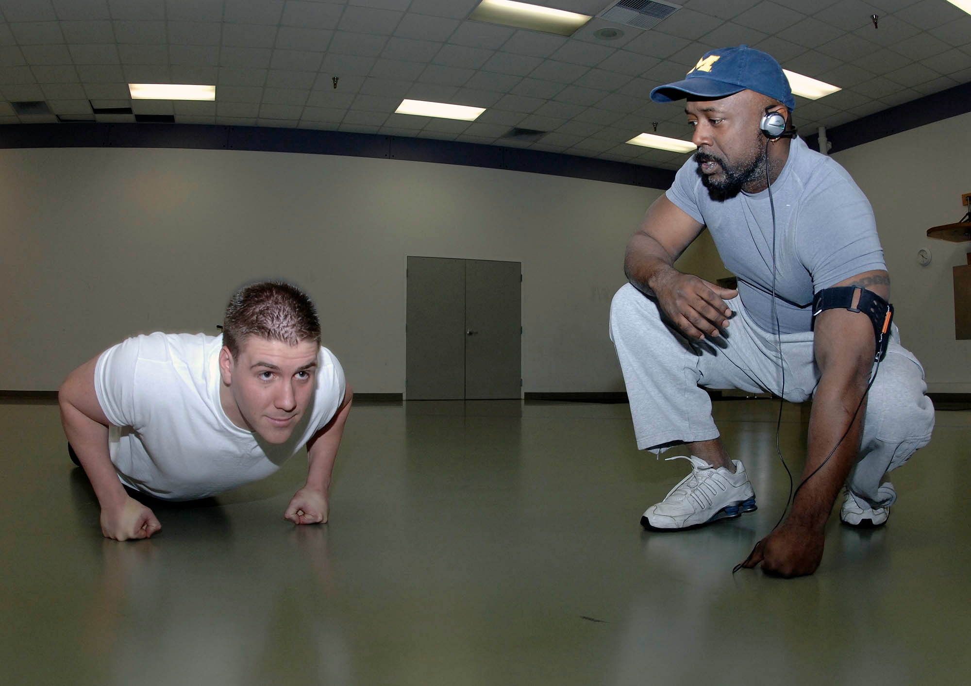 FAIRCHILD AIR FORCE BASE, Wash. – Jarrad Plunkett husband of Tech. Sgt. Alise Plunkett, 92nd Logistics Readiness Squadron, motivates Staff Sgt. Jeffery Gieras, 92nd Mission Support Squadron readiness manager, urging him to keep going at the push-up-athon on Dec. 6. Sergeant Gieras separated himself from competition by reaching the inconceivable count of 110 push-ups when the time had expired. The event took place in the base fitness center and hosted 15 contestants of all ages. Members raised money by gathering pledges then did as many push ups as they could in a two minute increment. The money raised is going to off set the price of Air Mobility Command annual awards. (U.S. Air Force photo/Staff Sgt. JT May III)