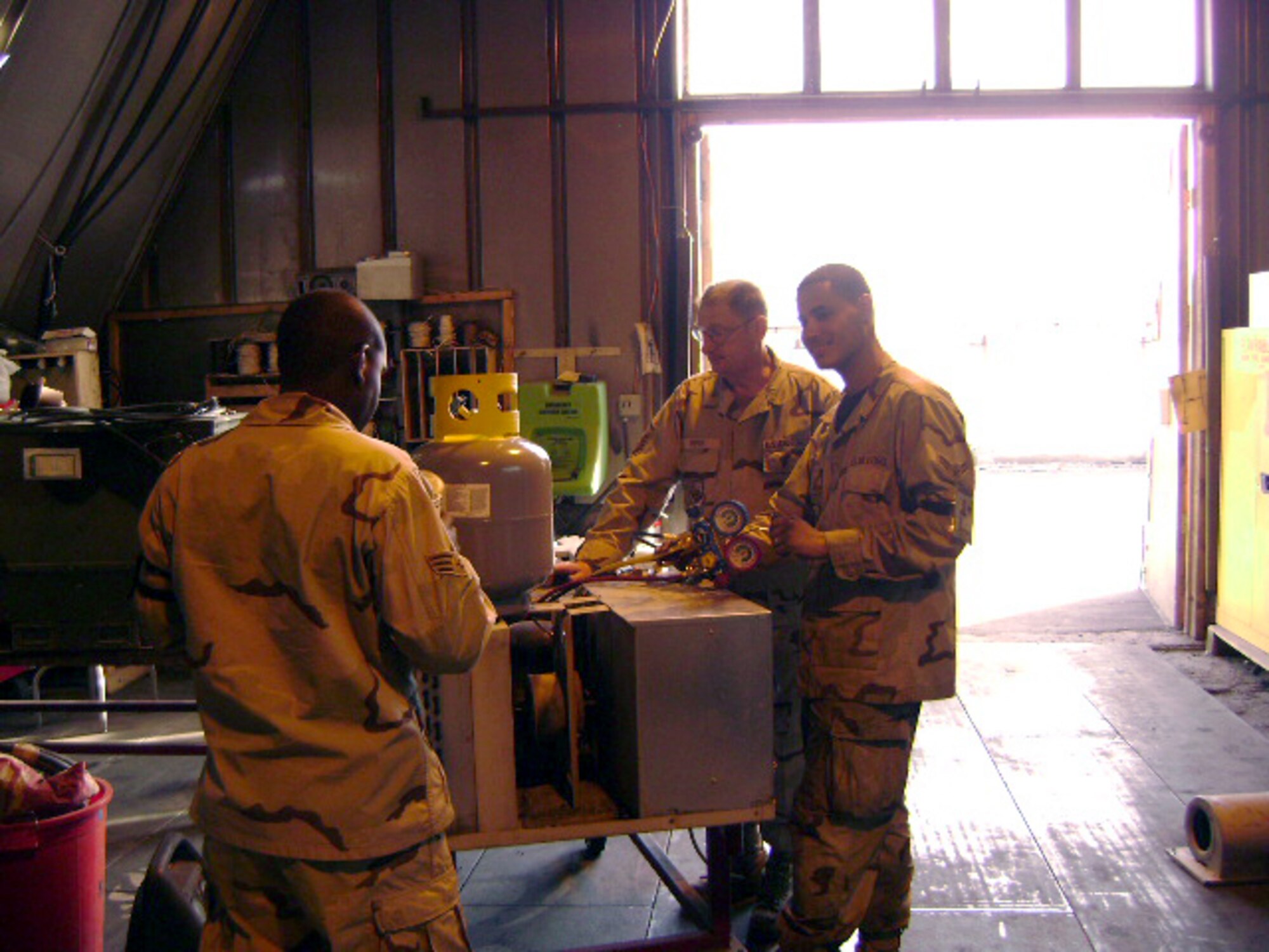 Master Sgt. Robert Piper (middle) and Airman 1st Class Rantor Ortiz (right), both with the 376th Expeditionary Civil Engineer Squadron deployed from Mountain Home Air Force Base, reclaim refrigerant from an engine control unit to protect the environment while deployed to Manas Air Base, Kyrgyzstan. (Courtesy photo)