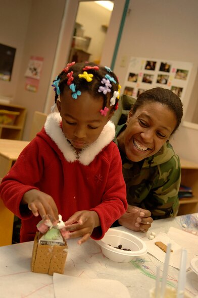 HANSCOM AFB, Mass. – The Child Development Center sponsored a parent and child activity on Dec. 7. Children in the pre-school program made gingerbread houses with their family members. Madison Whitehurst (left) adds the finishing touches to her gingerbread house while her mom, Maj. Pamela Howard looks on. (U.S. Air Force photo by Jan Abate)

