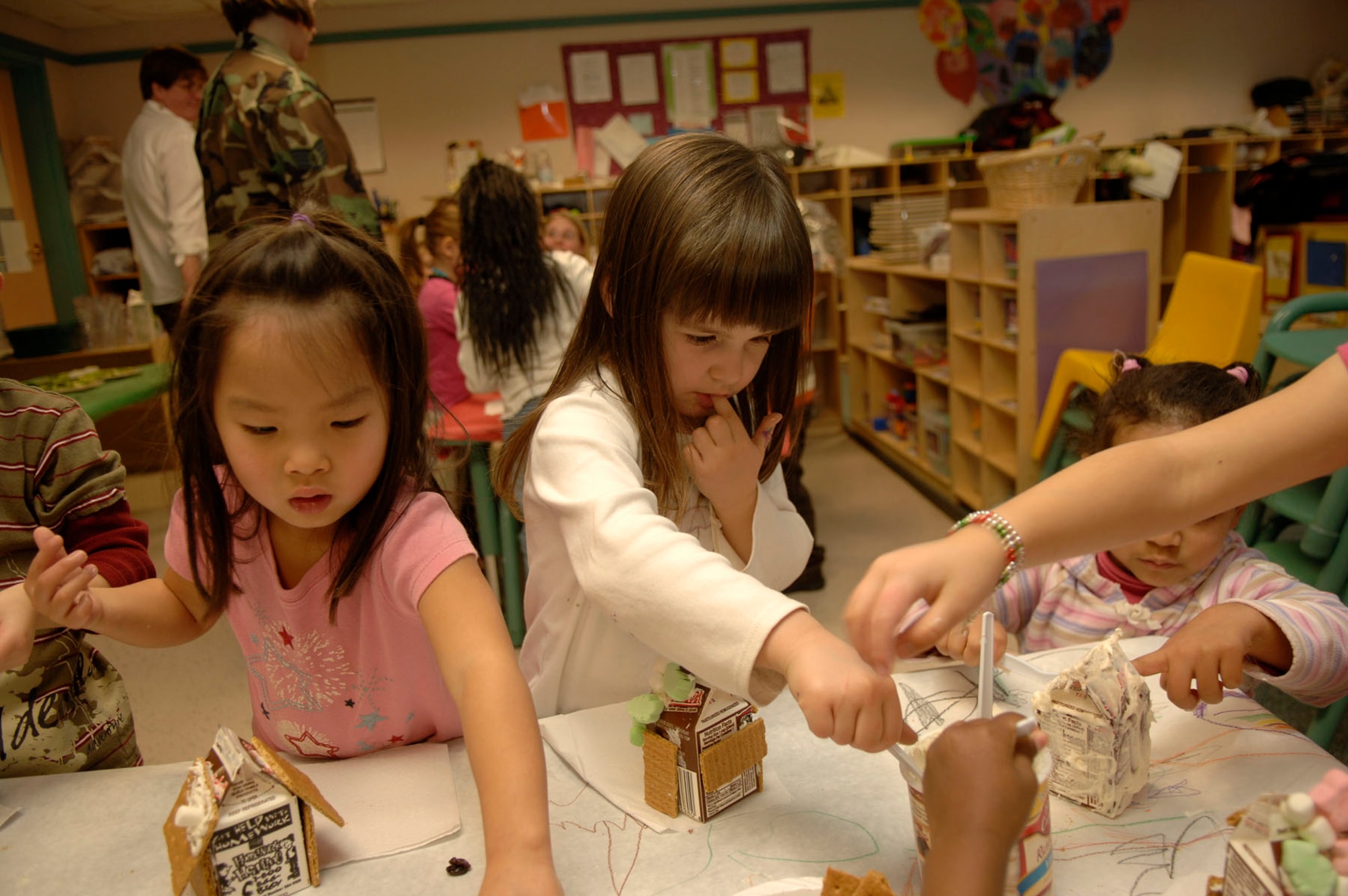 HANSCOM AFB, Mass. – Ashley Griffith (left) and Kaley Bergeron (right), pre-school students in Room 9 at the Child Development Center make gingerbread houses with their classmates on Dec. 7 at the Center. The event was a parent and child activity for children enrolled in the CDC program.  (U.S. Air Force photo by Jan Abate)


