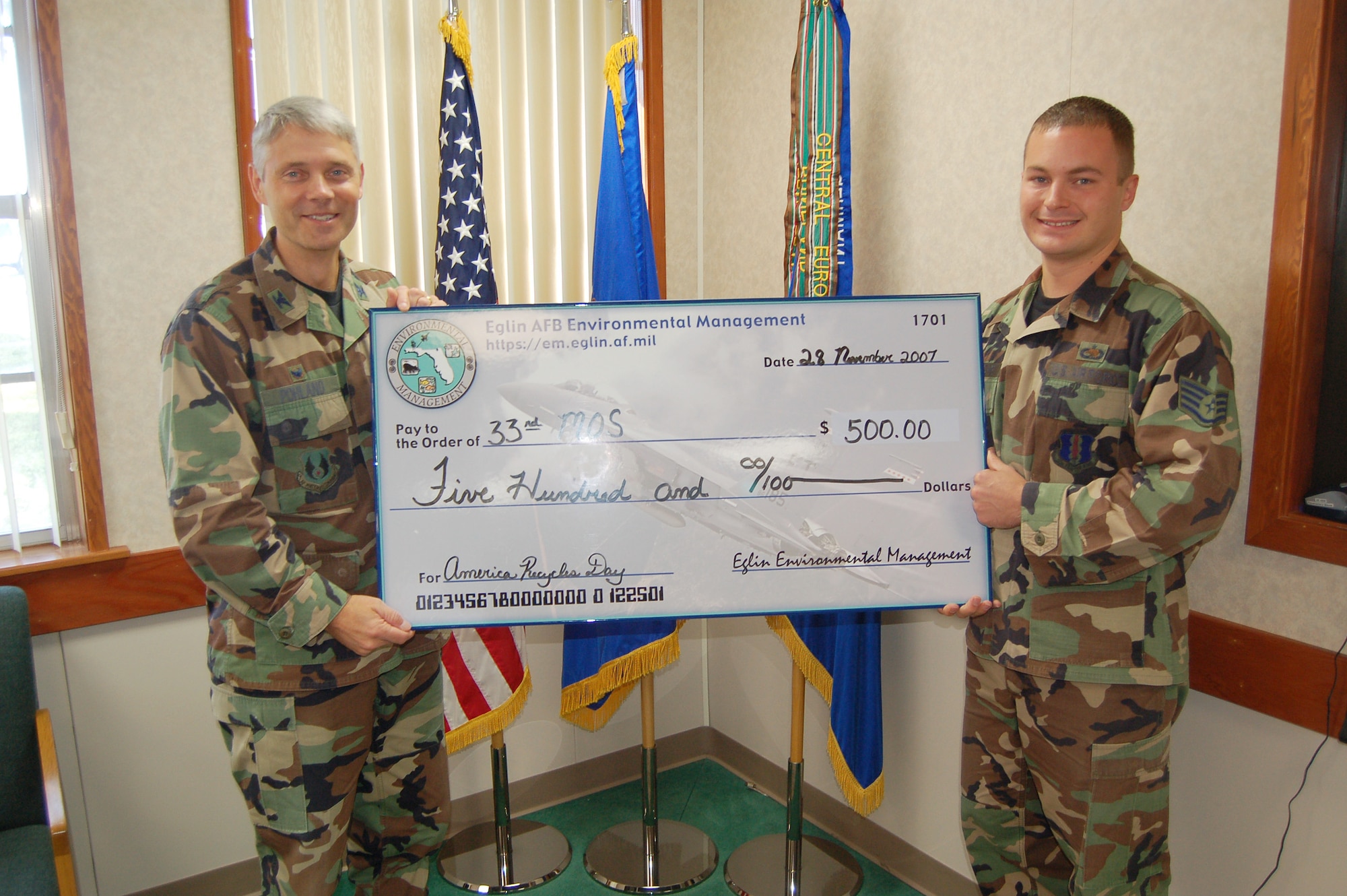 Colonel Eric Pohland, 96th Air Base Wing commander, holds the $500 first place check with Staff Sgt. Andrew Gamache, 33d Maintenance Group quality assurance inspector.  The 33d Maintenance Operations Squadron won first place in the third annual America Recycles Day aluminum can recycling contest. (U.S. Air Force photo by Jerron Barnett)