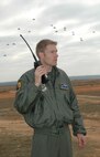 Paratroopers free-fall to the ground as Capt. Adam Shockley, a navigator with the 43rd Airlift Wing, listens on the ground during Operation Toy Drop. The 440th Airlift Wing, Air Force Reserve, supported the combined joint exercise with C-130 airlift. More than 1,050 paratroopers jumped during the exercise held at the Sicily Drop Zone at Fort Bragg, N.C. (U.S. Air Force photo/Lt. Col. Ann Peru Knabe)