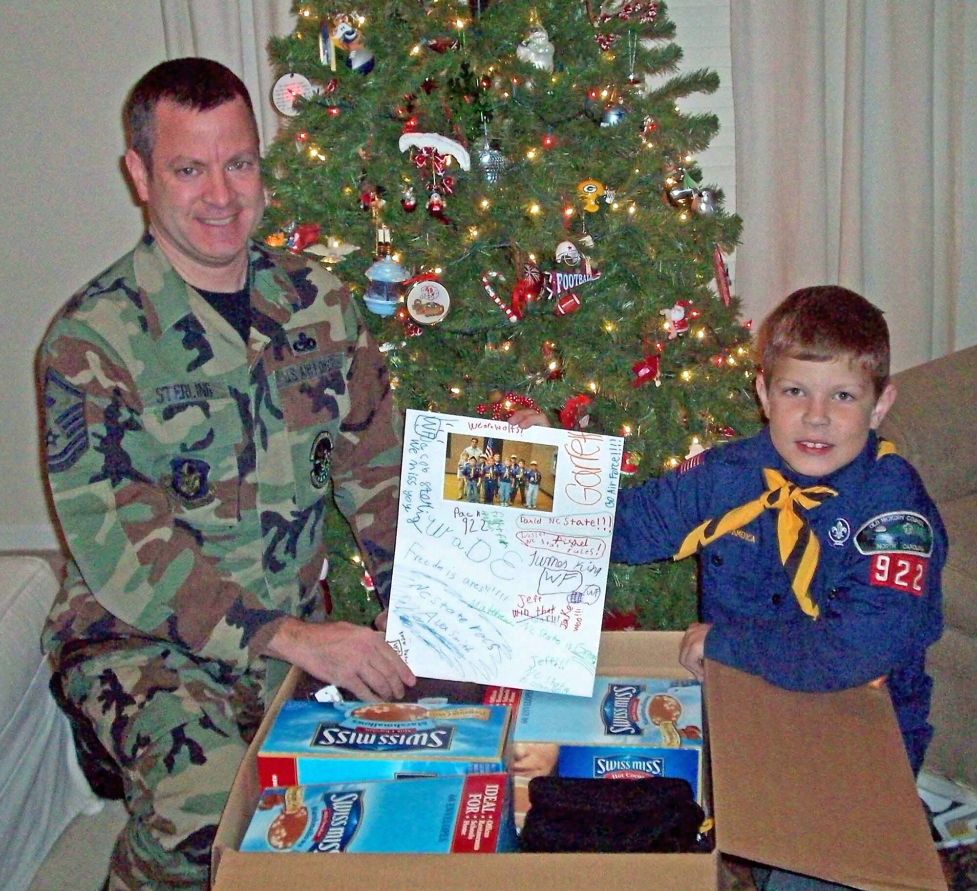 SEYMOUR JOHNSON AIR FORCE BASE, N.C. -- Master Sgt. Brian Sterling, a reservist with the 916th Maintenance Squadron, sits with his son Jacob, age 8, as they display the items collected by Jacob's Boy Scout Troop, Pack 922 out of Walkertown, N.C. Jacob's wolf den decided they wanted to help out troops overseas during the holiday and collected items ranging from electric blankets to hot chocolate mix. The young scouts collected items over a three week period and then went on AnyAirman.com to find some deployed troops from Seymour Johnson that they could support.