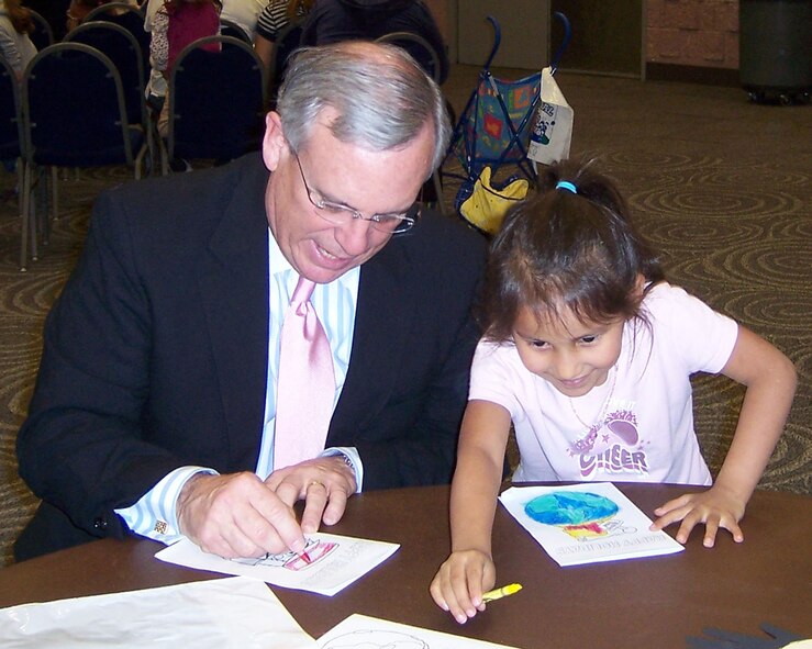 Norm Archibald, Mayor of Abilene, colors a card for the troop overseas along with Marissa Flores,Dyess dependent, during the annual HEB Feast of Sharing.  