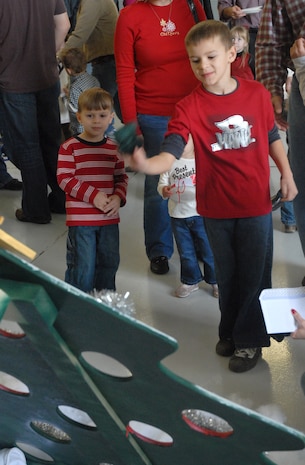Cameron Pavelschak, 7, son of Maj. James Pavelschak, tosses a bean bag into a tree during the Children's Holiday Party Saturday. (U.S. Air Force photo/Airman Melissa White)