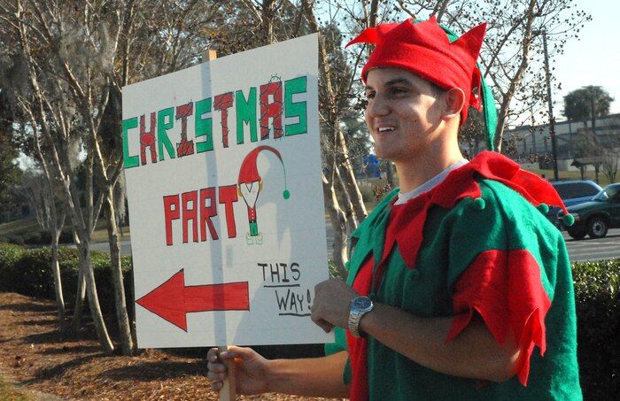 Senior Airman David Methvin, 16th Airlfit Squadron, stands in front of the Fitness and Sports Center to direct people toward the Children's Holiday Party while wearing a festive elf costume Saturday. (U.S. Air Force photo/Airman Melissa White)