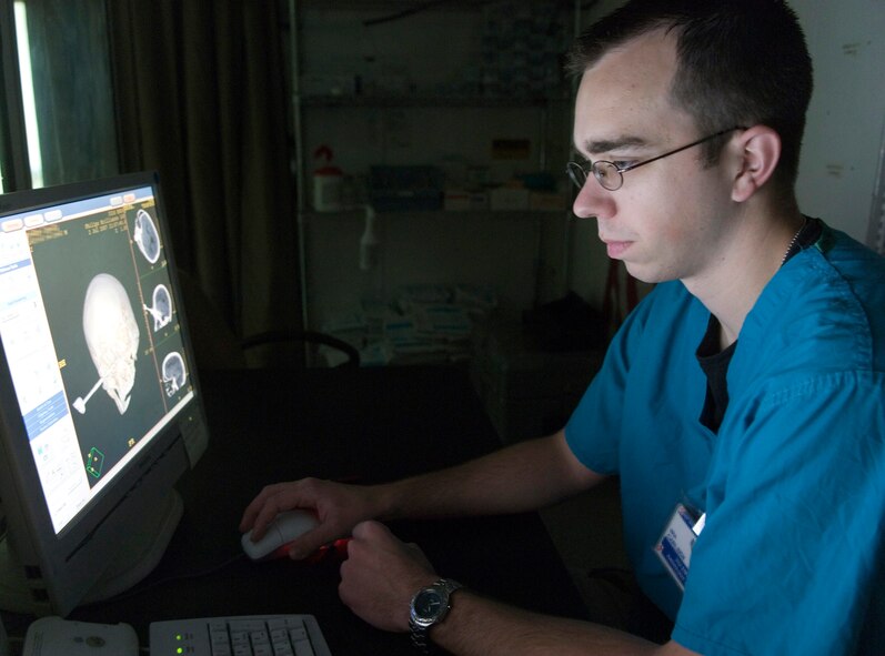 Senior Airman Dustun Carlsen references a past CT scan of a patient with a knife lodged in his head at the Air Force Theater Hospital at Balad Air Base, Iraq. Airman Carlsen is a radiology technician with the 332nd Expeditionary Medical Group, and is deployed from Lackland Air Force Base, Texas. (U.S. Air Force photo illustration/Senior Airman Travis Edwards) 