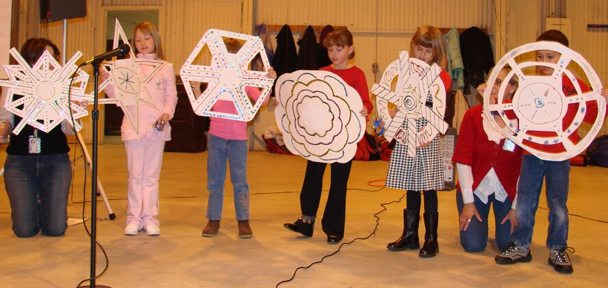 Children enrolled in the School-Age Program perform a snowflake play during "Breakfast with Santa" Dec. 8 in Hangar 170. The children also sang holiday songs during to 350 Team Vance family members that attended the event. (U.S. Air Force photo by Tech. Sgt. Mary Davis)