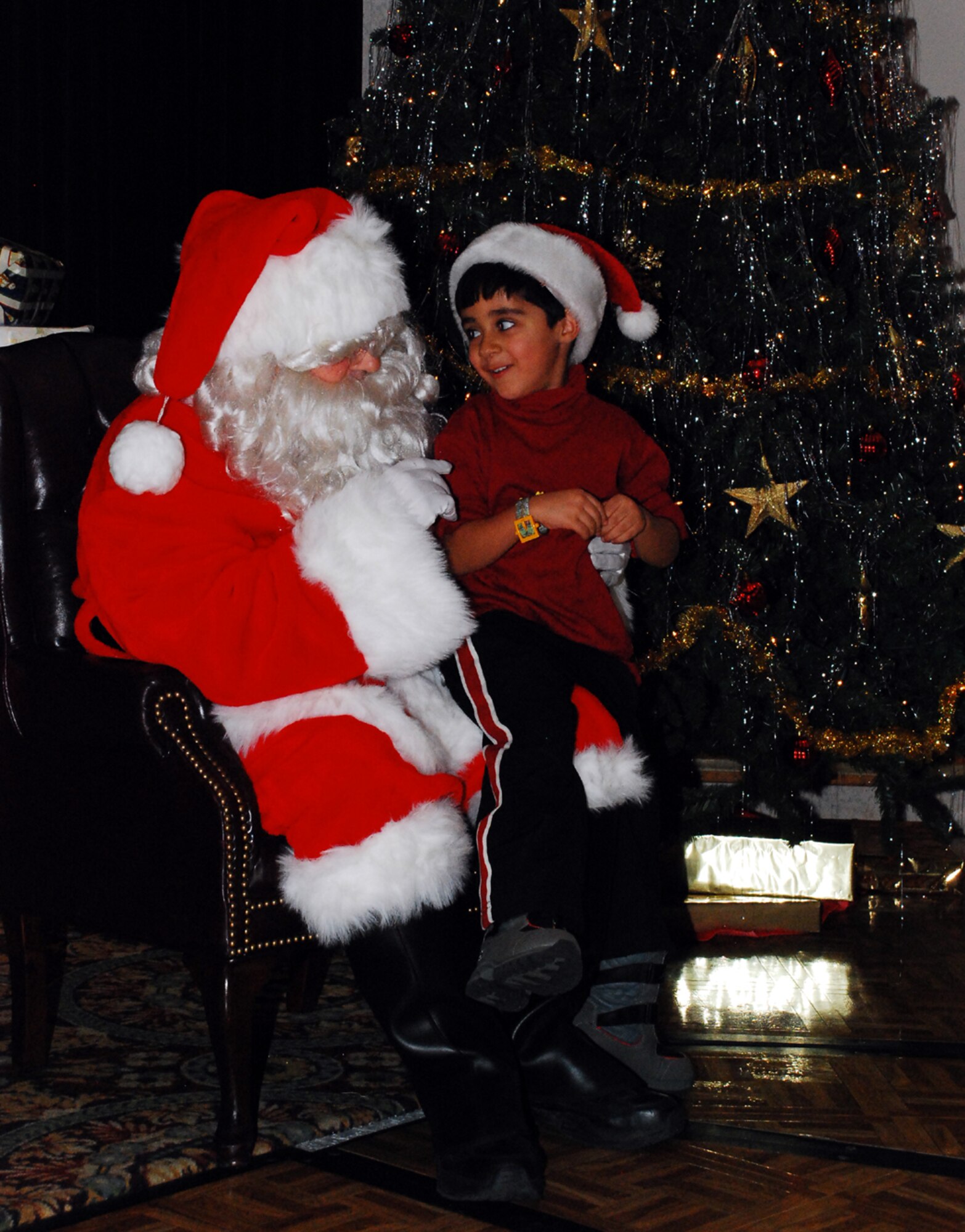 Eddy Lopez, 5, shared his Christmas wishes with Santa Claus during the annual Hearts Apart Christmas Party at The Club. After clearing his busy schedule, Santa made a surprise visit to the families of deployed Airmen here. (U.S. Air Force photo/Airman 1st Class Rebekah Phy)   