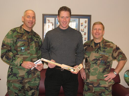 HANSCOM AFB, Mass. – Former Boston Bruins player Bob Sweeney (center) visited Hanscom on Dec. 11 to deliver tickets for an upcoming Boston Bruins game to Airmen honored at last week’s Heroes’ Homecoming celebration. The former Bruins player took time to sign autographs and meet with base personnel. Col. Tom Schluckebier, 66th Air Base Wing commander (left), and Brig. Gen. Pete Hoene (right), 350th Electronic Systems Wing commander met with Mr. Sweeney during his base visit.(U.S. Air Force photo by 2nd Lt. Michaela Walrond)