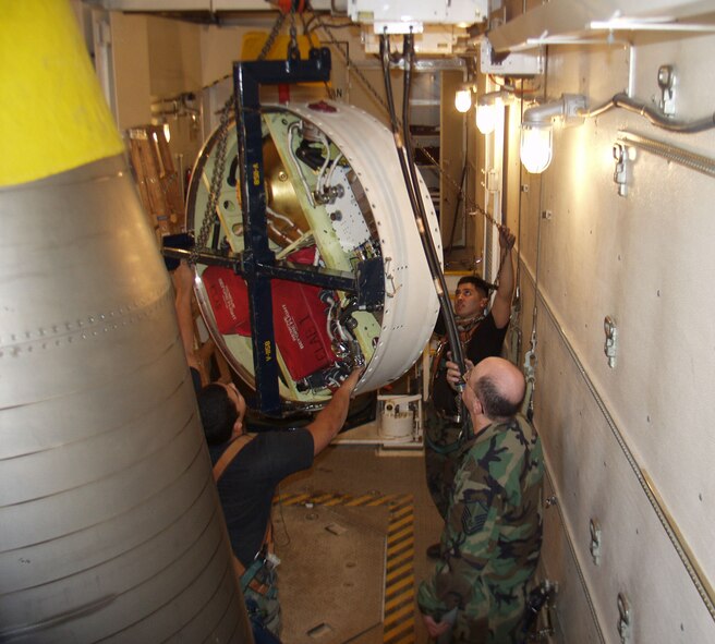 Master Sgt. Maxwell Jackson, 341st Missile Maintenance Squadron team critical task supervisor, Staff Sgt. Preston Yockeman, 341st Missile Maintenance Squadron team cageman, and Senior Airman David Burress, 341st Missile Maintenance Squadron team top side technician,  perform Missile Guidance System tilt procedures to maneuver the MGS to the rear of the two re-entry systems in the payload transporter van on site. (U.S. Air Force photo/Master Sgt. Maxwell Jackson)