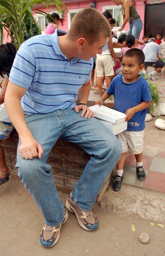 COMAYAGUA, Honduras – Air Force 1st Lt. Brian Robertson asks a young Honduran boy how he likes his new pair of shoes, a gift from U.S. Southern Command and Joint Task Force-Bravo.  Servicemembers from both commands delivered more than 130 pairs of shoes to Hogar de Niños Tierra Santa orphanage here Dec. 8.  (U.S. Air Force photo by Staff Sgt. Austin M. May)