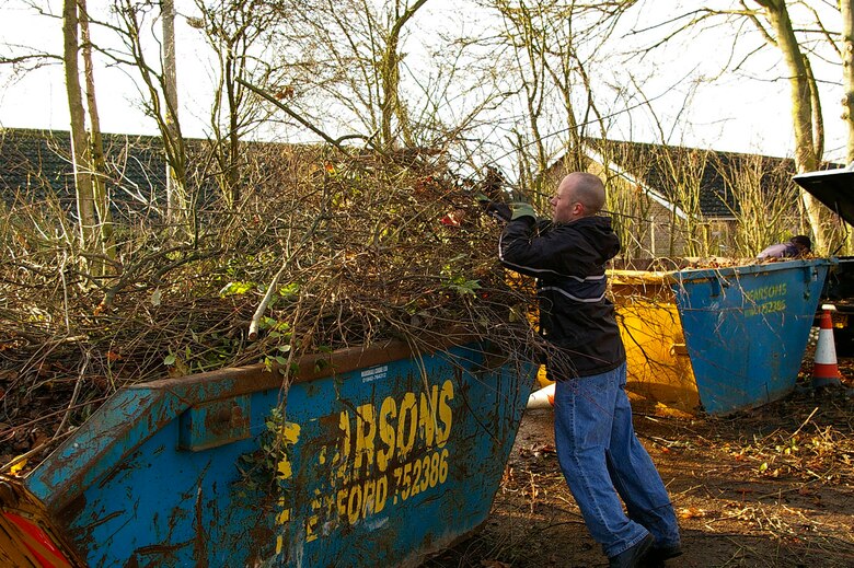 Tech. Sgt. Brian Bowers, 95th RS, sweeps leaves into piles, ready to put into a barrow, at Riverside Middle School in Mildenhall Dec. 7. (U.S. Air Force photo by Karen Abeyasekere)