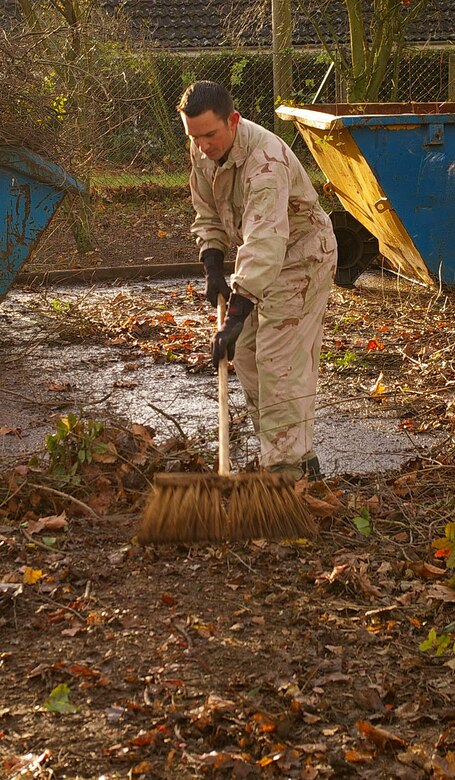 Master Sgt. Larry Haynes, left, and Senior Airman Sean Ellis, both 95th RS, transfer piles of leaves into the back of a truck, ready to transfer to the skip, Dec. 7 at a local school in Mildenhall. The squadron members spent two days cleaning up a large area of the school grounds. (U.S. Air Force photo by Karen Abeyasekere)