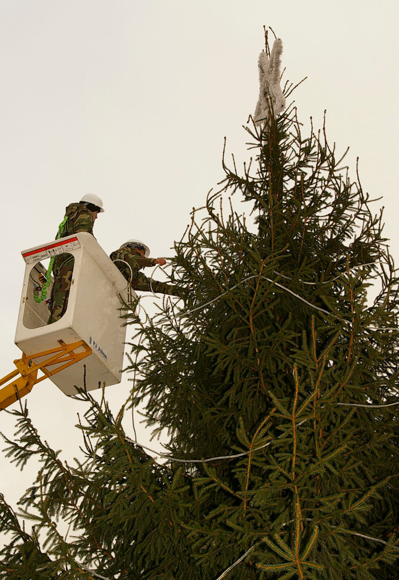 Staff Sgt. David Stollings, left, and Airman 1st Class Aaron Hildebrand, both 100th Civil Engineer Squadron Electric Shop, put the lights on RAF Mildenhall's Christmas tree Dec. 4. The tree light ceremony is Thursday at 4 p.m. (U.S. Air Force photo by Karen Abeyasekere)