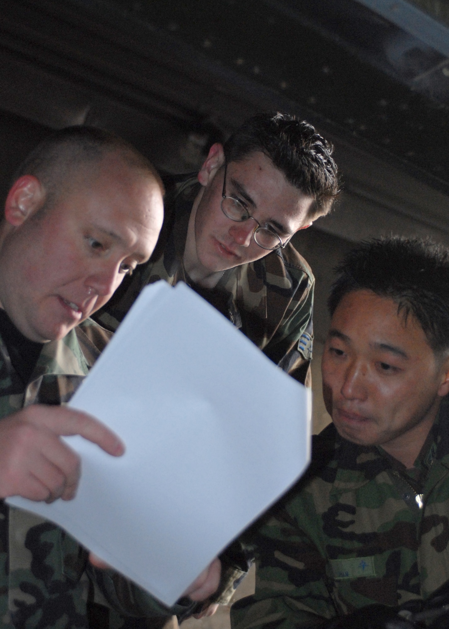 CHUNG JU AIR BASE, South Korea-- Republic of Korea Air Force Tech. Sgt. Su Min, 17th Fighter Wing (right), Tech. Sgt. Jason Smith and Senior Airman Tyler Brown, assigned to the 8th Maintenance Group review an F-4 training guide Dec. 7 here. The training is a way for U.S and Republic of Korea Airmen to develop teamwork learning from each other to improve war fighting capabilities. (U.S. Air Force Photo/Staff Sgt Araceli Alarcon) 