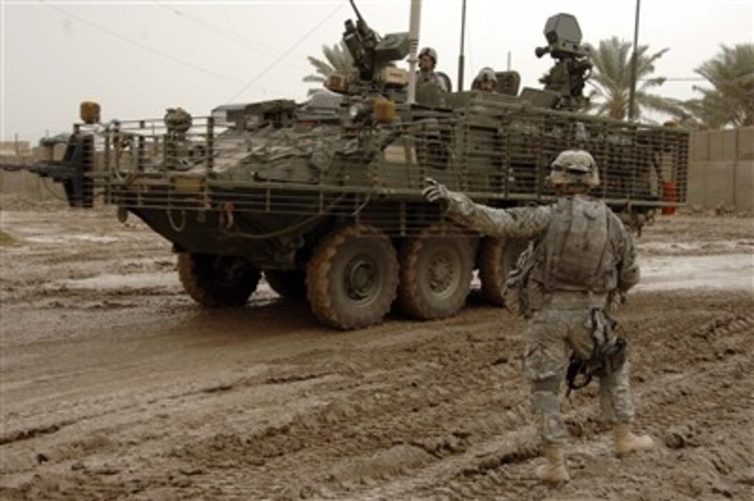 U.S. Army Command Sgt. Maj. Gregory Frias points in the direction he wants a Stryker Light Armored Vehicle to stage as it navigates a muddy road during a stop at a combat outpost in Muquadiah, Iraq, on Dec. 6, 2007.  Frias is attached to the 2nd Battalion, 23rd Infantry Regiment, 4th Brigade Combat Team, 2nd Infantry Division.   