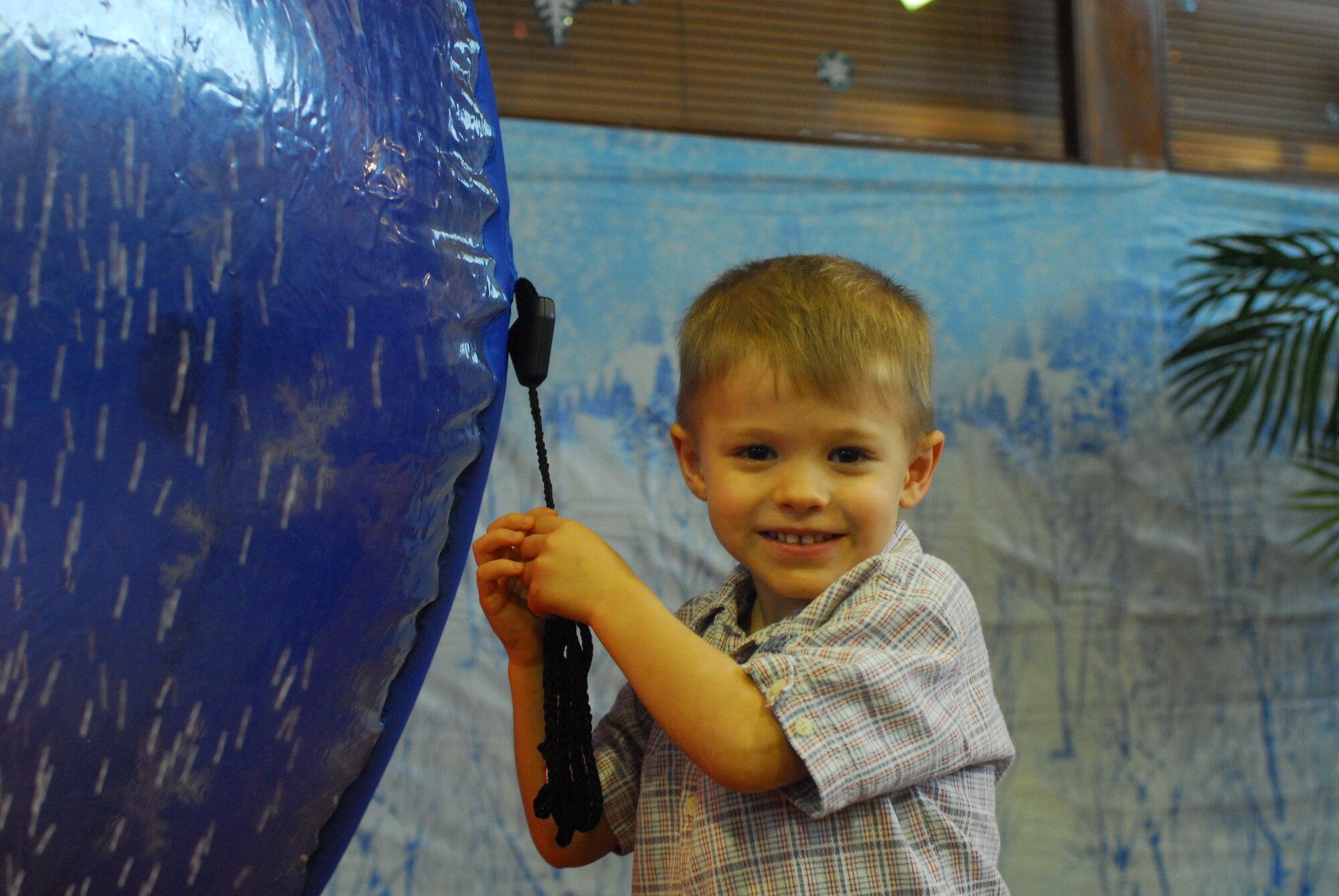 Joshua Sampson the son of Master Sgt. Kevin Sampson holds on to the tie string for a Holiday display at Wednesday night’s Airman Family Readiness Center Heart’s Apart Holiday party for deployed spouses.  (U.S. Air Force Photo/Staff Sgt. Erin Smith)