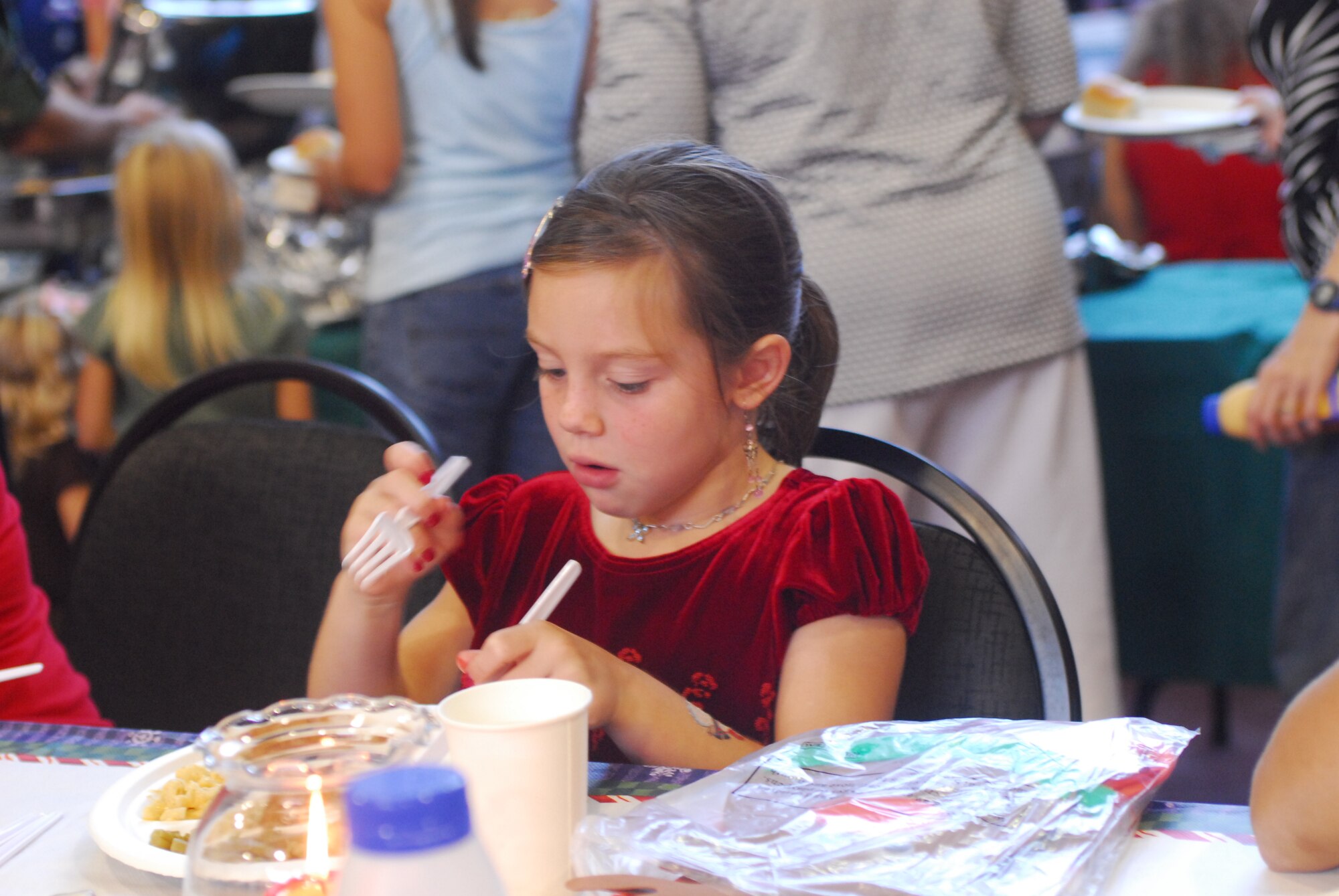 Bethany Viventi, the daughter of deployed Tech. Sgt. Anthony Viventi, 535th Airlift Squadron enjoys the holiday meal at Wednesday night’s Hearts Apart Airman Family and Readiness Center Holiday Party in the Family Services Lani (U.S. Air Force Photo by SSgt Erin Smith).

